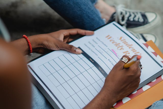 Free From above crop anonymous African American female student writing weekly report