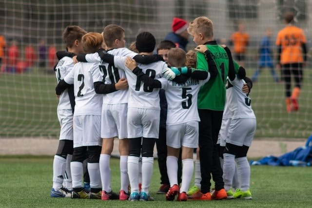 Kids soccer team huddling on the field