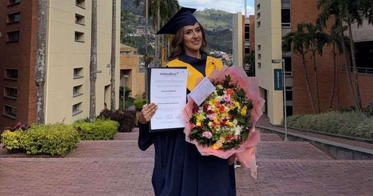 Ana Lucía Giraldo con toga y birrete, sosteniendo su diploma y un ramo de flores en el campus de la Unilasallista.