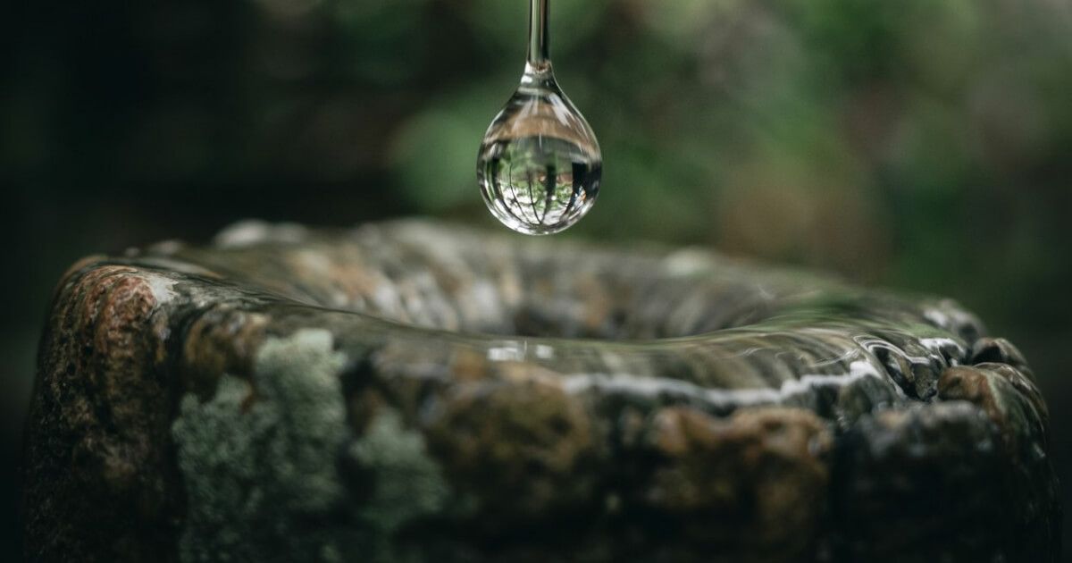Close-up of a water droplet falling onto an eroded stone.